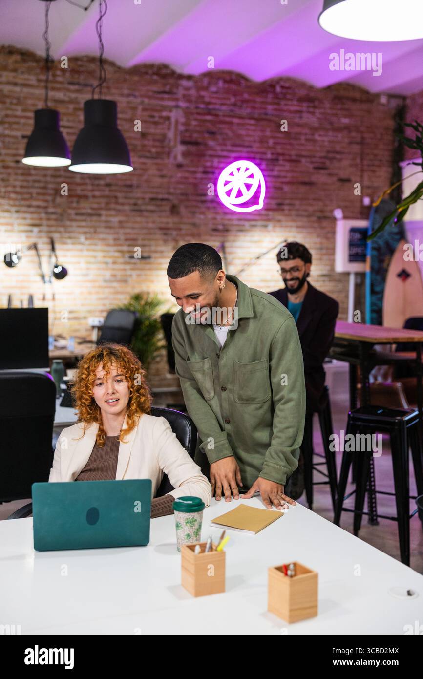 Multi ethnic team collaborating on laptop in modern office Stock Photo