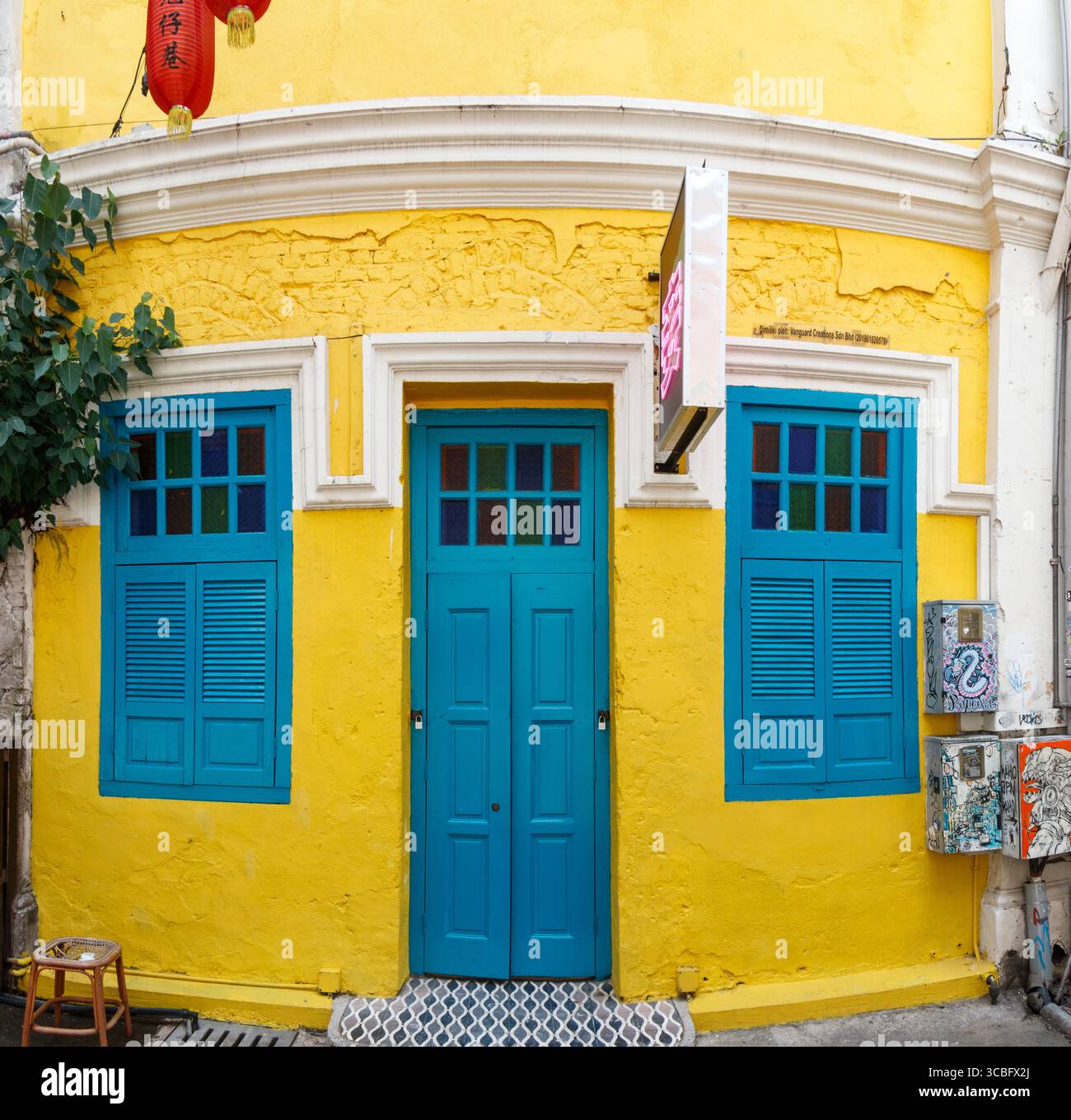Vibrant yellow heritage building facade with blue doors and shutters windows, featuring a red lantern contrasting colours , kuala lumpur, malaysia Stock Photo