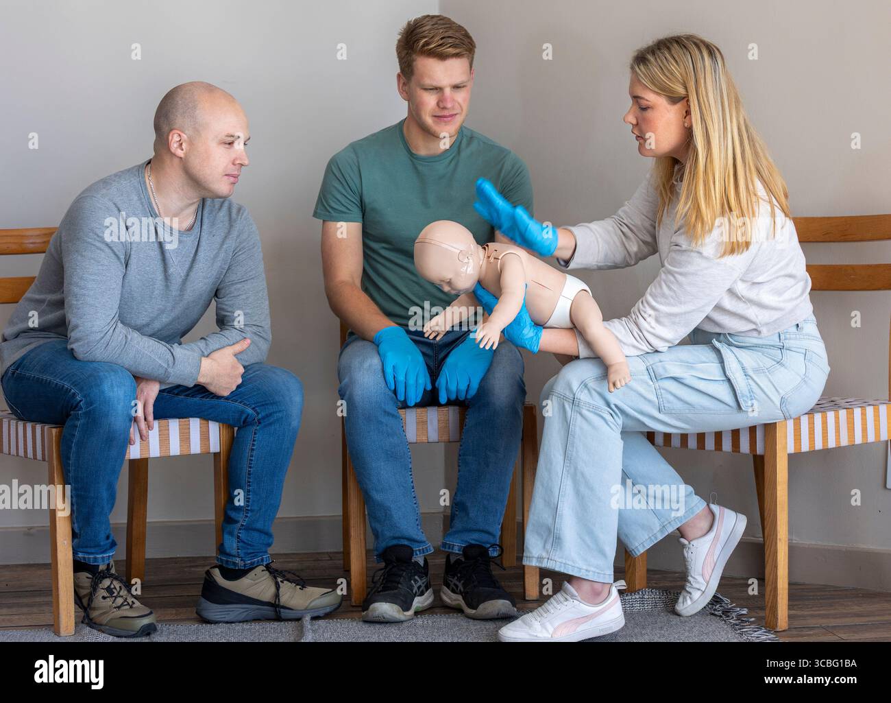 Female first aid instructor demonstrating the blockage release technique for infant choking by delivering back blows on an infant Basic Life Support ( Stock Photo