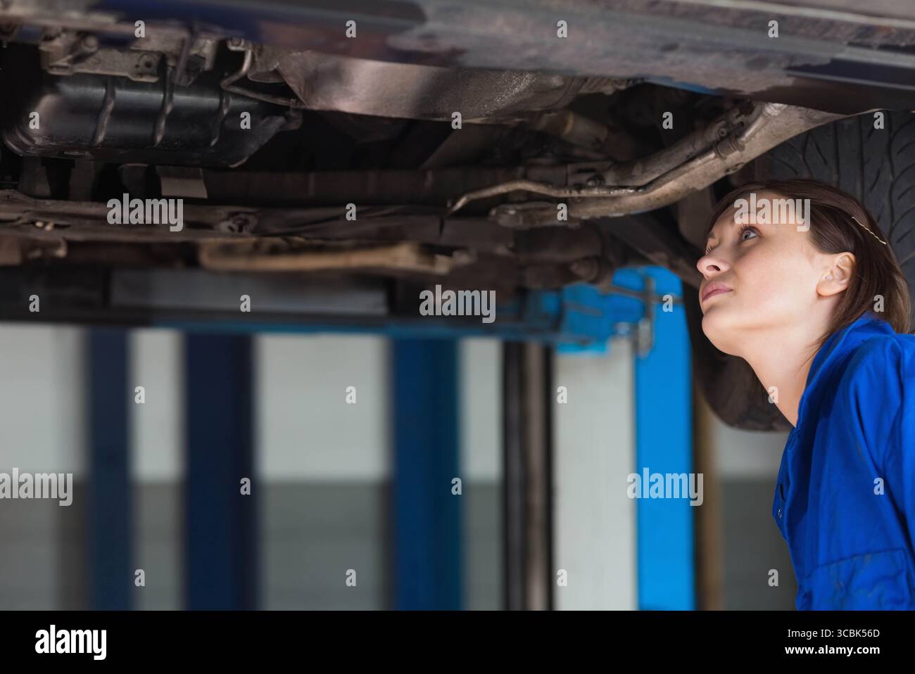 Hydraulic lift raising car to expose suspension and exhaust pipes in ...