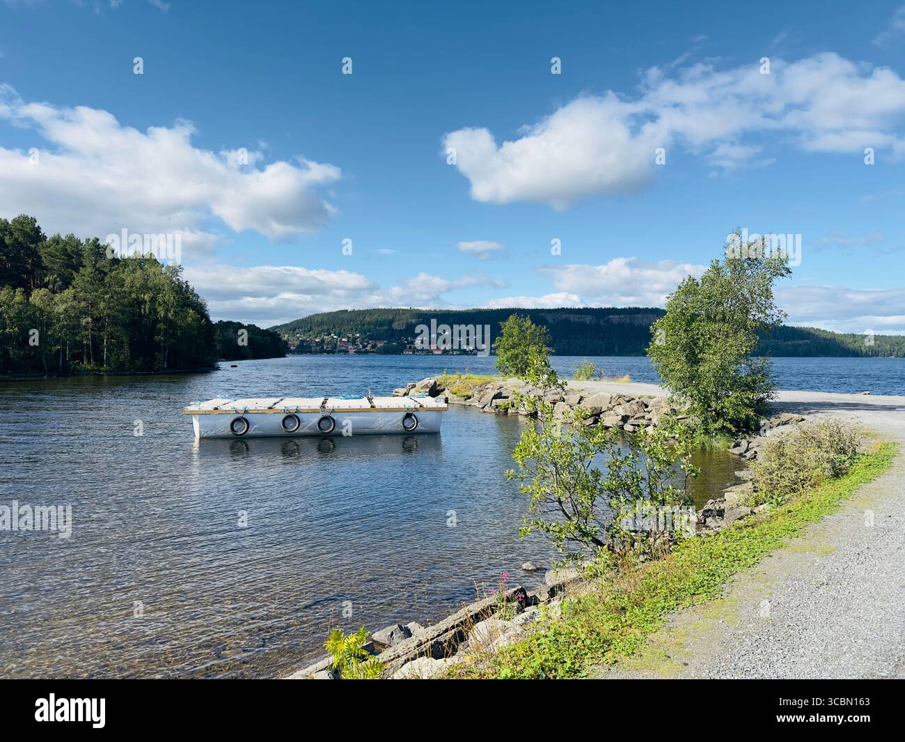 A beautiful lakeside scene with a dock under a blue sky filled with clouds. - Smartphone Captured Stock Image