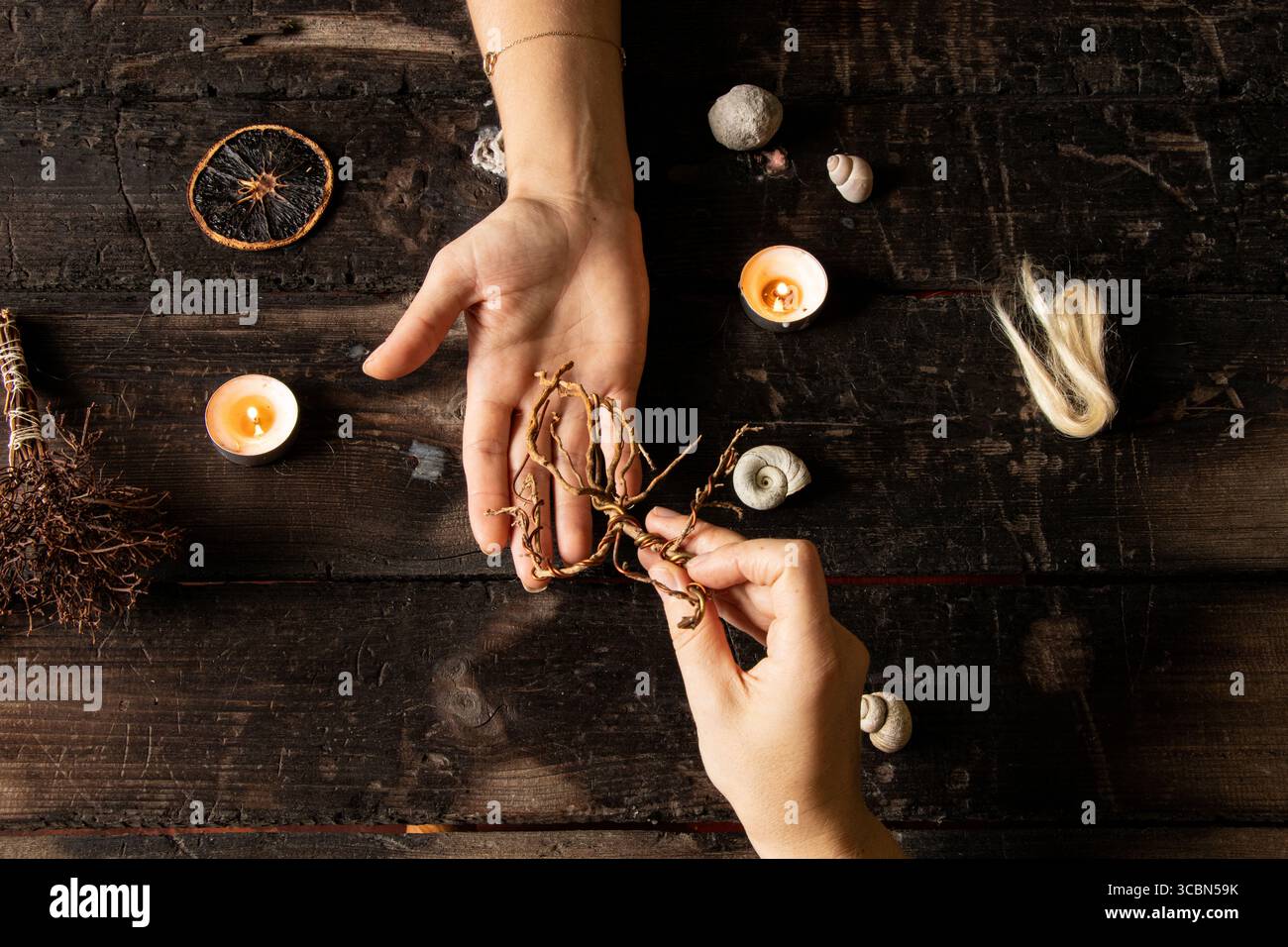 Female hands surrounded by shells and candles, roots, strands of hair ...