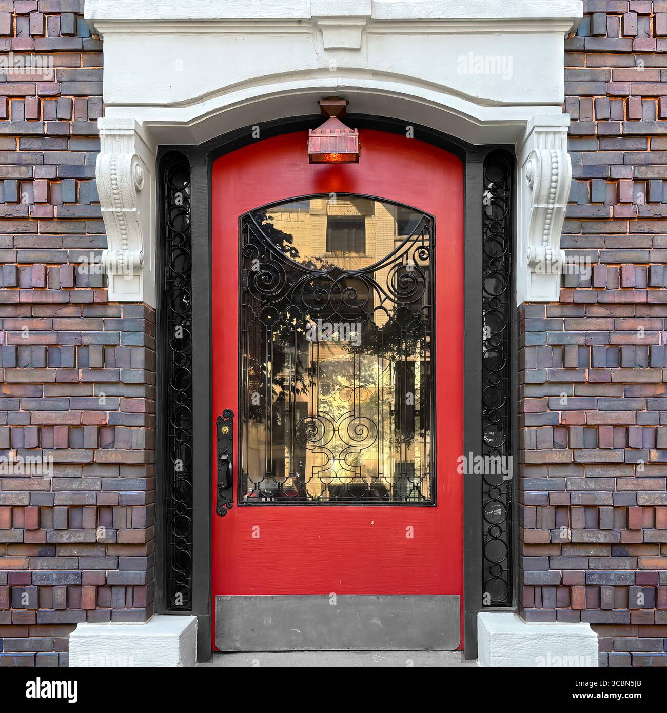 Elegant Chicago red doorway framed by ornate black wrought iron and decorative white trim, reflecting city life in its glass panels. - Smartphone Captured Stock Image
