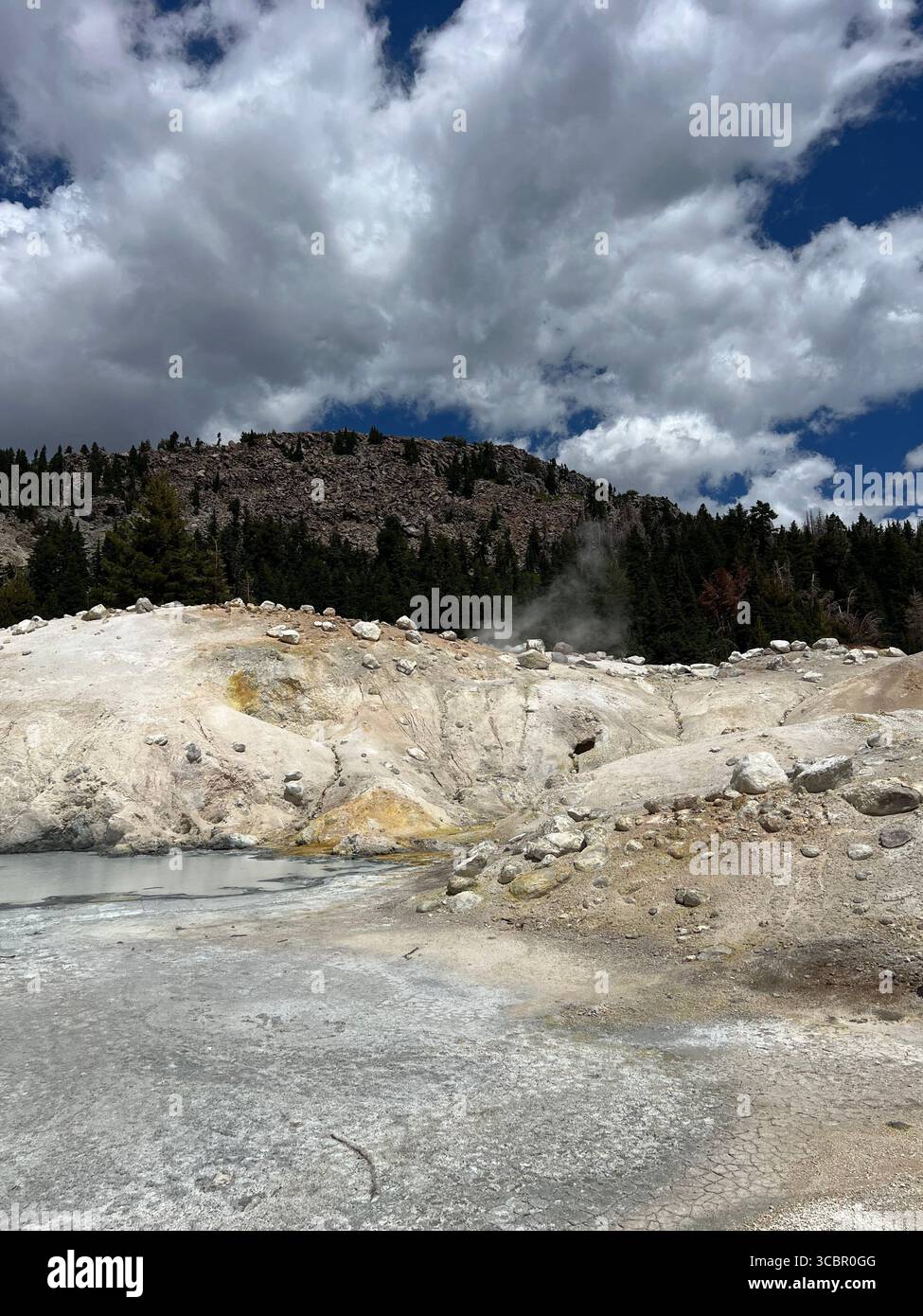 Geothermal landscape at Bumpass Hell in Lassen Volcanic National Park with steaming vents, rocky terrain, and dramatic clouds above the wilderness. - Smartphone Captured Stock Image