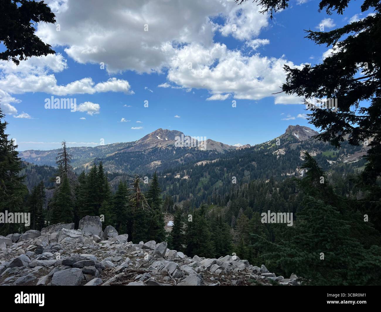 Majestic summer view of Lassen Peak in California with leftover snow, dramatic sky, forest, and rocky slopes. Scenic mountain national park landscape. - Smartphone Captured Stock Image