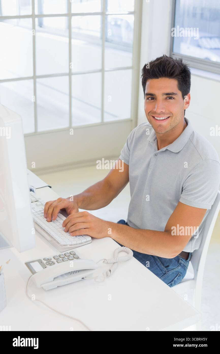 Man typing on keyboard at office desk using computer monitor and ...