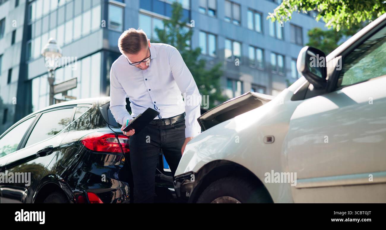 Insurance Adjuster Inspects Car Damage Using Tablet After Accident Stock Photo
