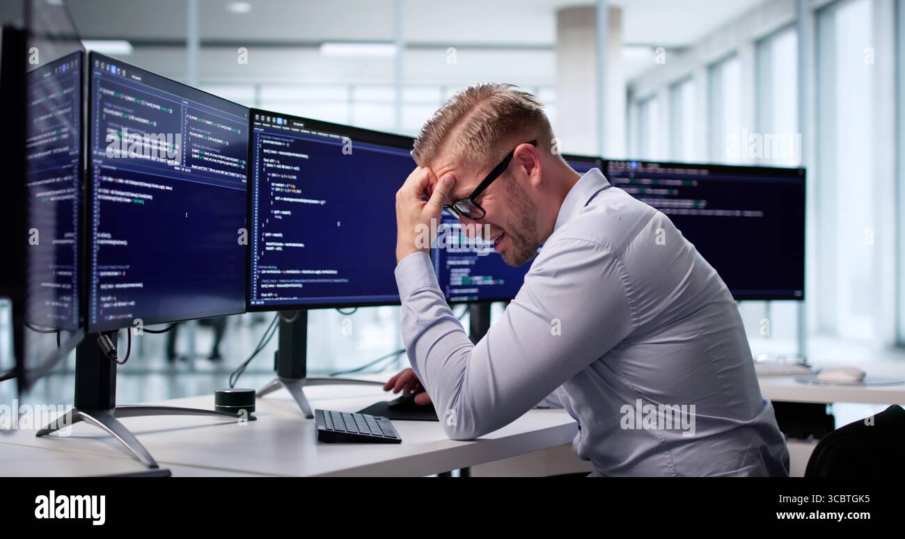 Sad Web Developer Frustrated With Coding In Office, Staring At Screen. Possible Professions: Programmer, Coder Stock Photo