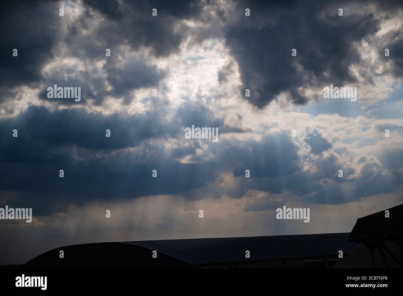 Dramatic dark clouds with penetrating rays of light. Stock Photo