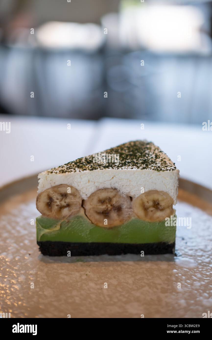 Matcha green tea banoffee pie, served on plate. It is a dessert made from banana, whipped cream, thick caramel sauce with crumbled base. Stock Photo