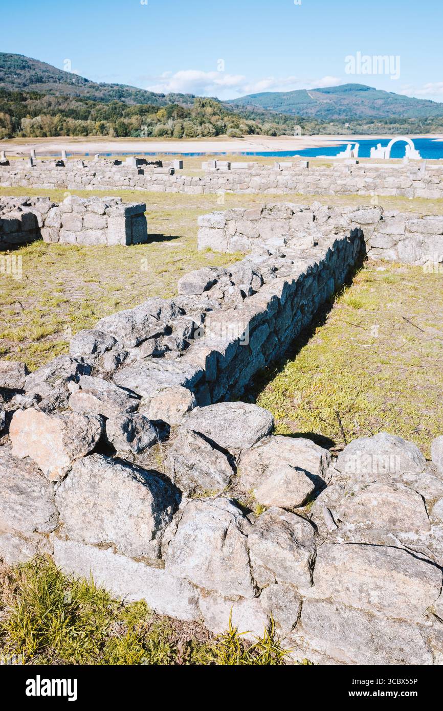 The stone arches of a roman ruin against a forest and lake background ...