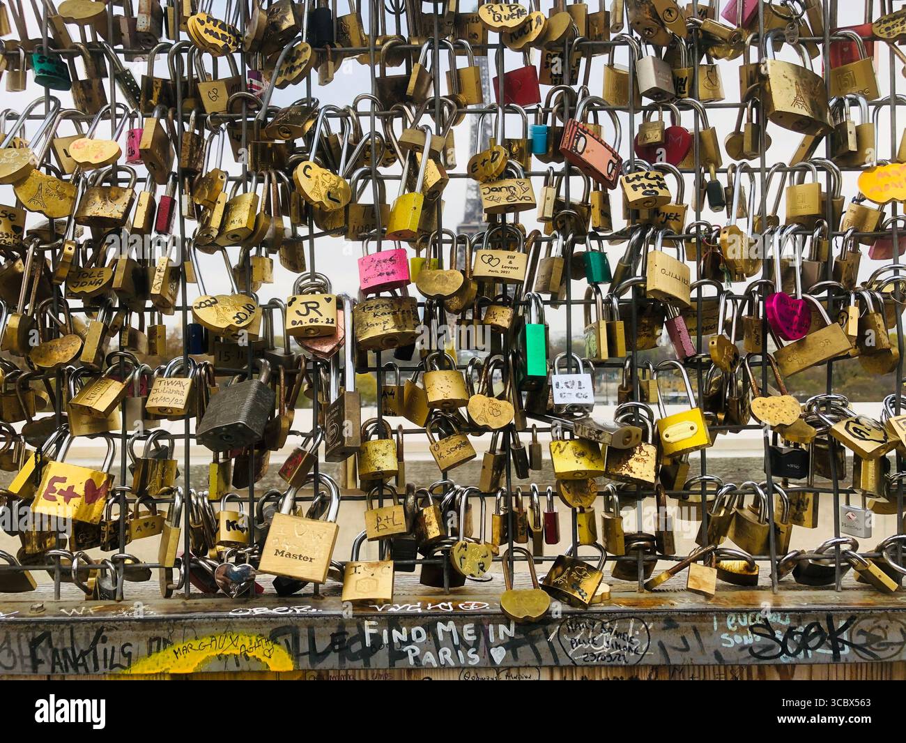 Love padlocks on Paris fences symbolize eternal romance, with many placed on iconic bridges like Pont des Arts and near Sacré-Cœur. - Smartphone Captured Stock Image