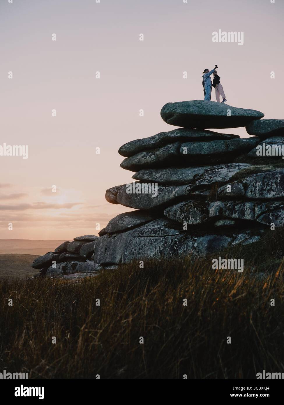 Figures enjoying the sunset on the granite tor on Stowes Hill, Minions, Bodmin Moor, Cornwall England UK Stock Photo