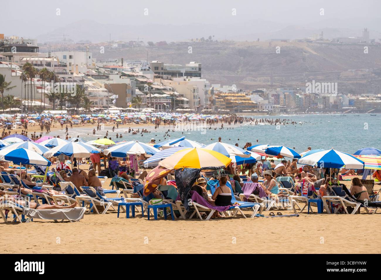 Las Palmas, Gran Canaria, Canary Islands, Spain. 9th August, 2025. Tourists, many British, join locals trying to keep cool on a packed city beach in Las Palmas as hot Saharan winds blow in from nearby Africa. Red heatwave alerts have been activated across all the Canary Islands for the weekend and early next week. The temperature at midnight in Agaete on Gran Canaria didn't drop below 34 degrees Celcius. Credit: Alan Dawson/Alamy Live News Stock Photo