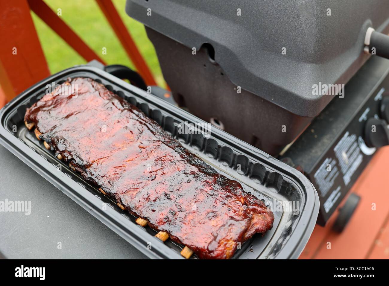 A slab of bbq ribs next to a gas grill on a patio deck Stock Photo - Alamy