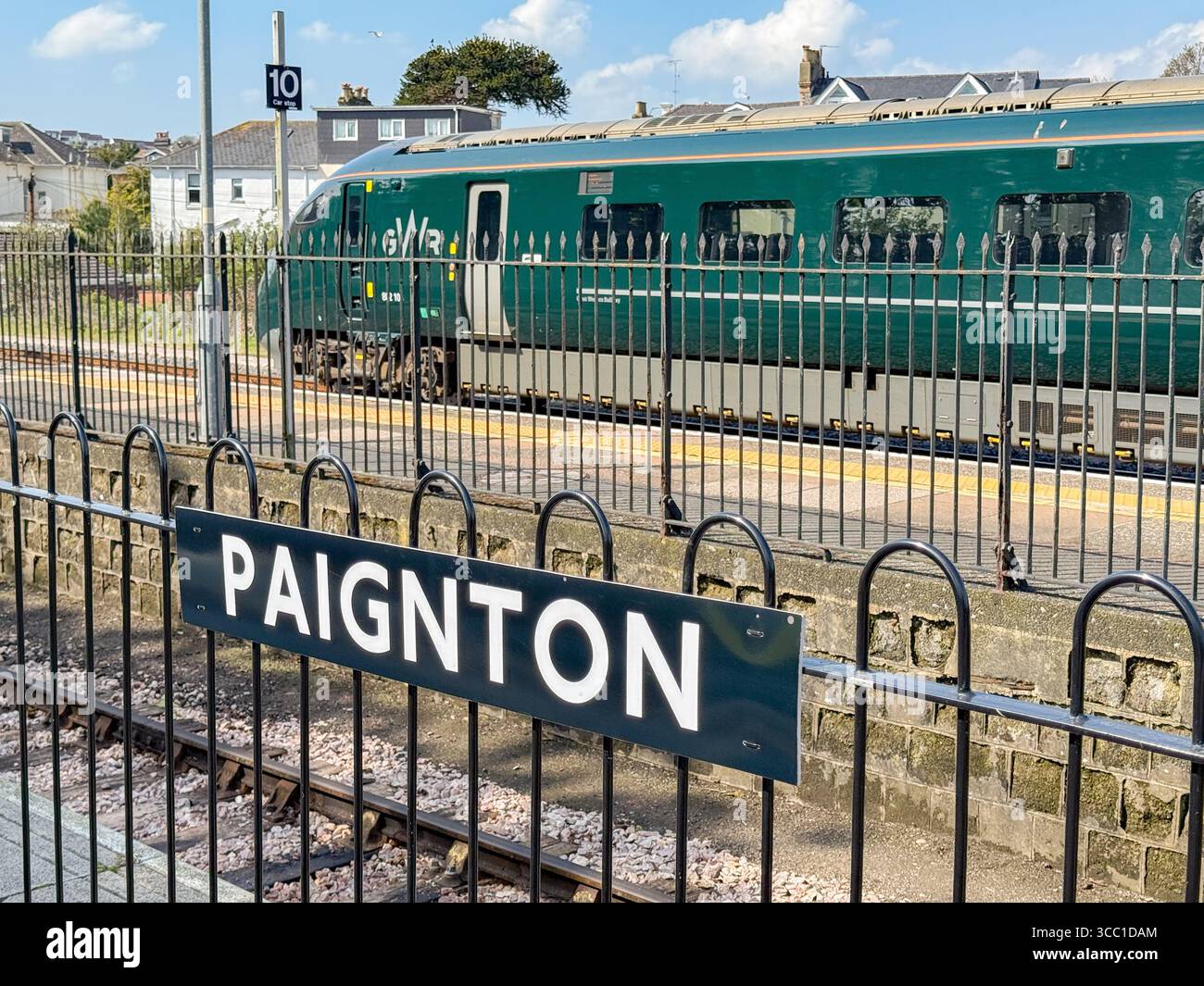 Paignton, Devon, England, UK - 24 April 2025: Station name sign on a platform at Paignton Railway Station with a Great Western Railway GWR train - Smartphone Captured Stock Image