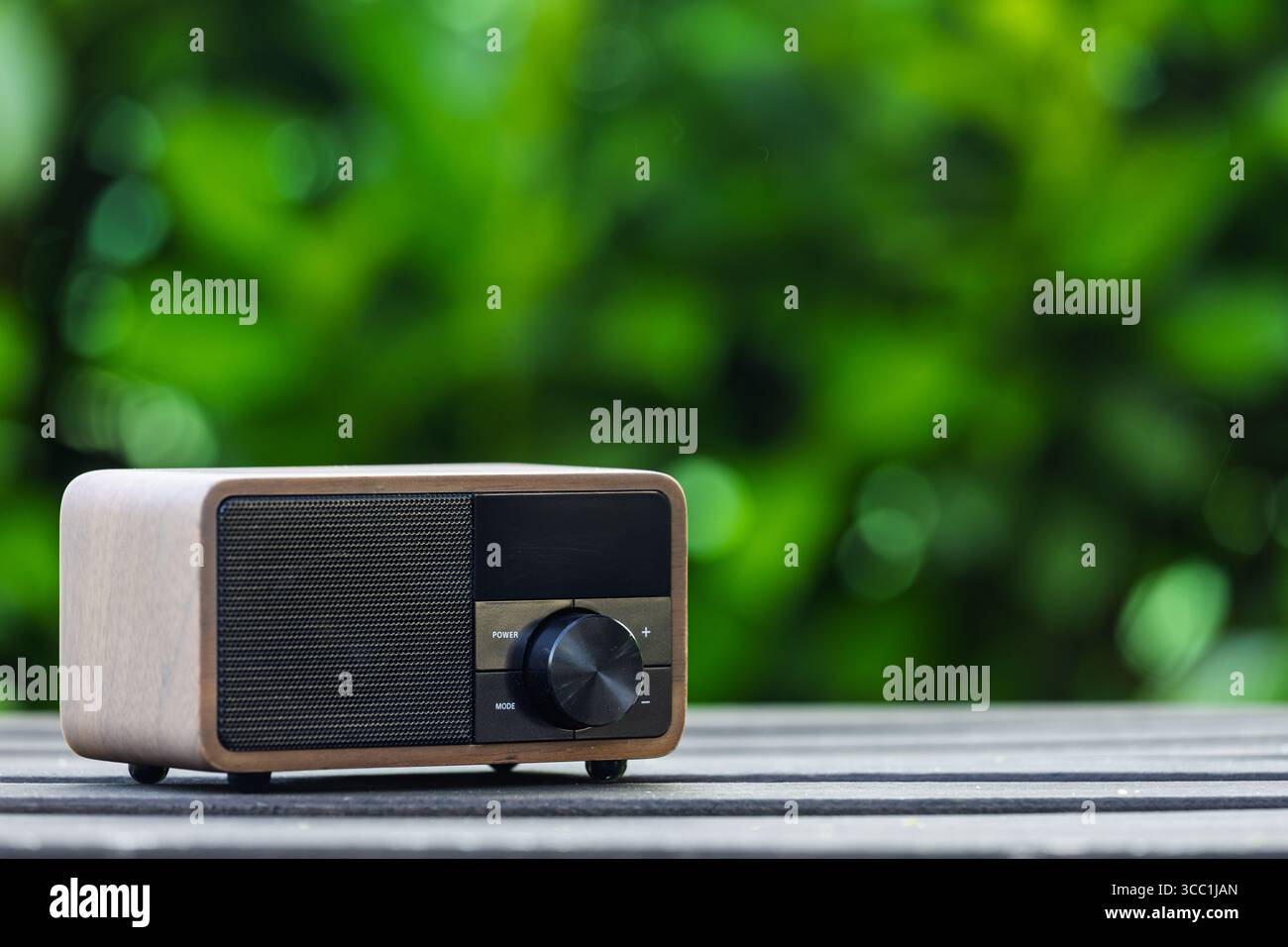 VINKOVCI, CROATIA, 06.13.2025:A close-up shot of a vintage green radio resting on a wooden table, with a lush, blurred green background creating a pea Stock Photo