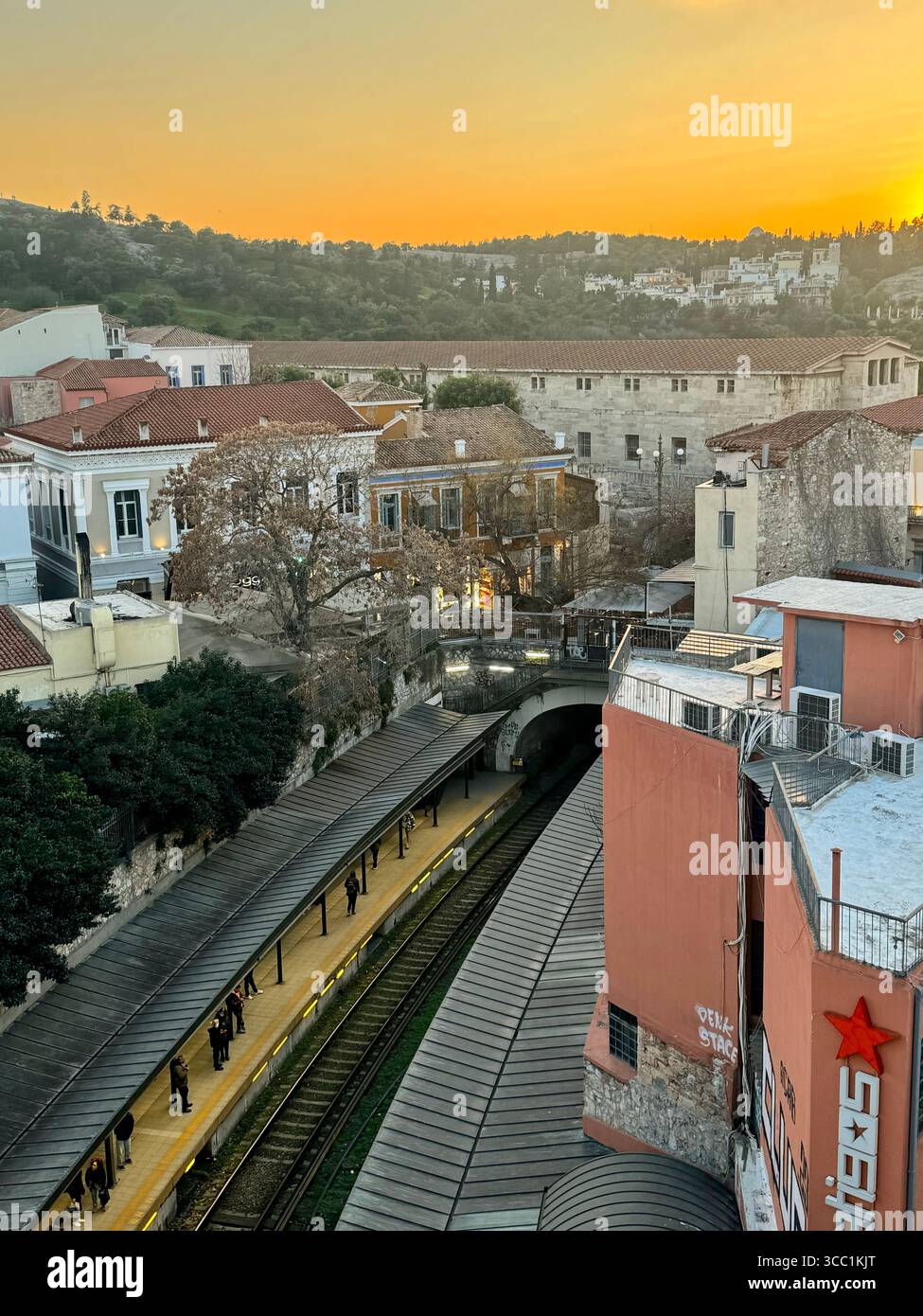 Sunset over Athens with a metro station and railway tracks in the foreground. - Smartphone Captured Stock Image
