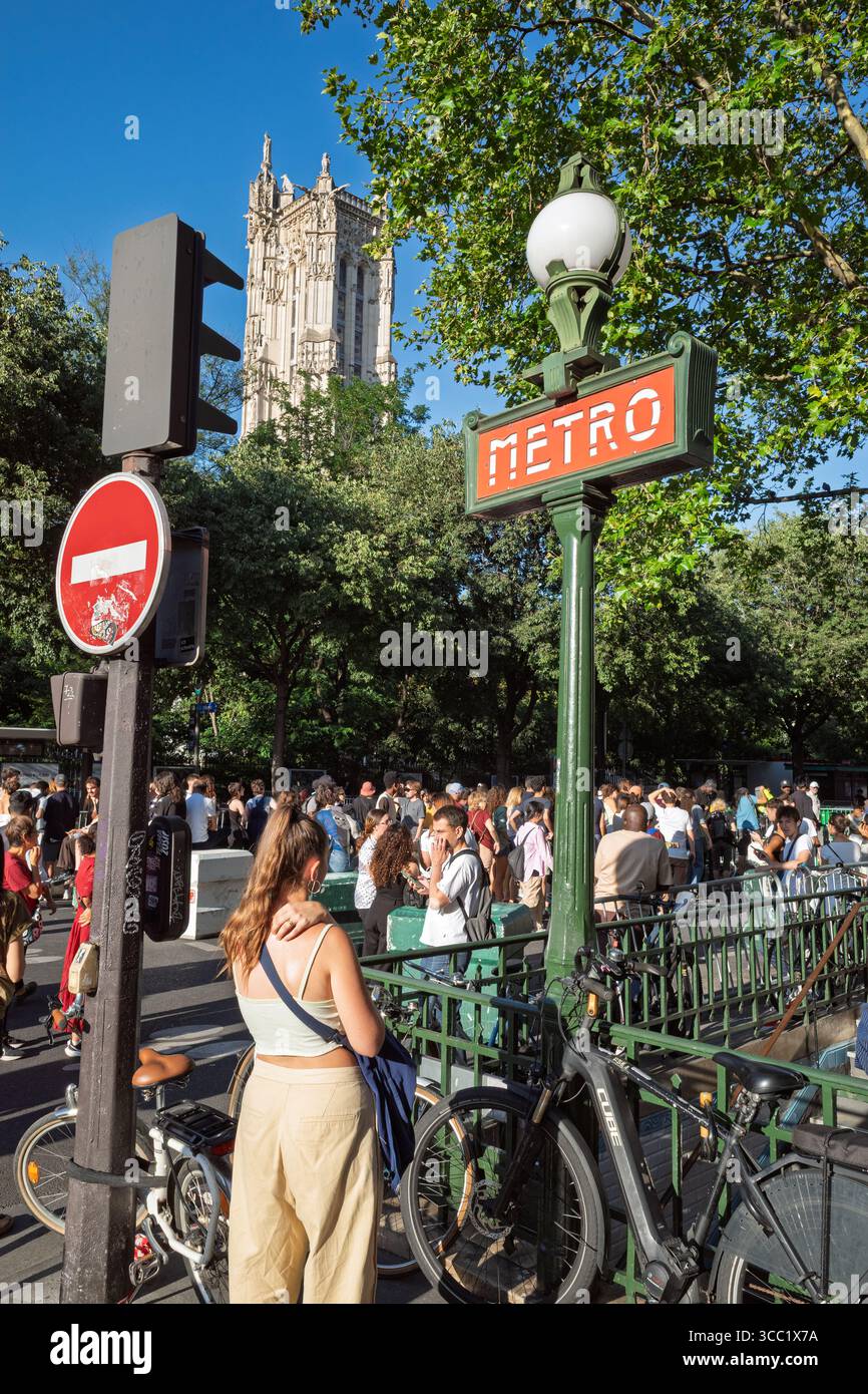 An iconic Paris Metro sign in the foreground with the historic Tour ...