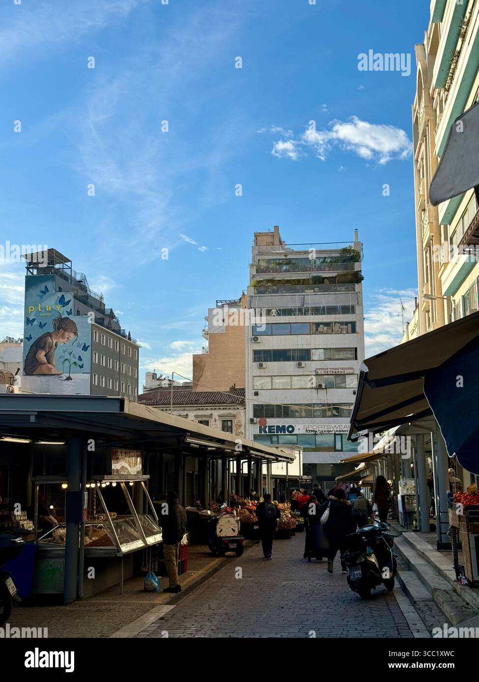 Street market scene in Athens, Greece, with vendors, shoppers, and urban buildings under a bright blue sky. - Smartphone Captured Stock Image