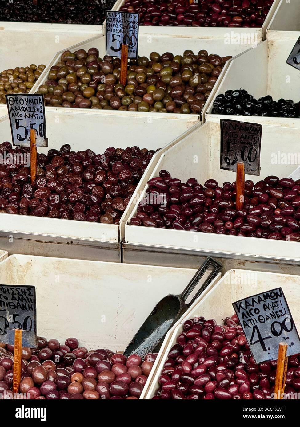 A colorful olive stand at a street market in Athens, Greece, showcasing a variety of local olives in crates. - Smartphone Captured Stock Image