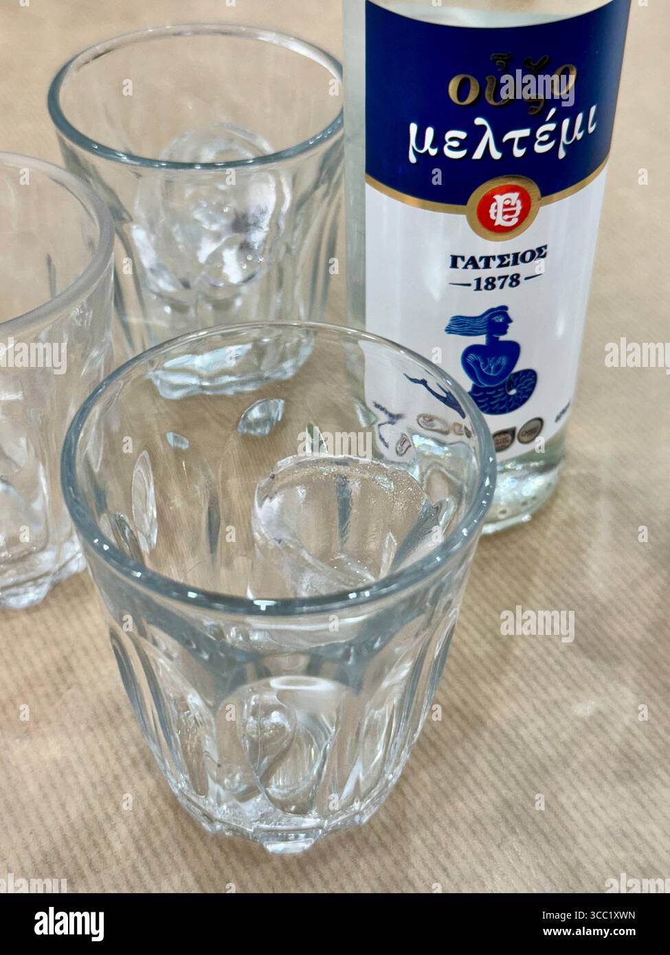A bottle of Ouzo and empty glasses ready for a traditional Greek drink experience. - Smartphone Captured Stock Image
