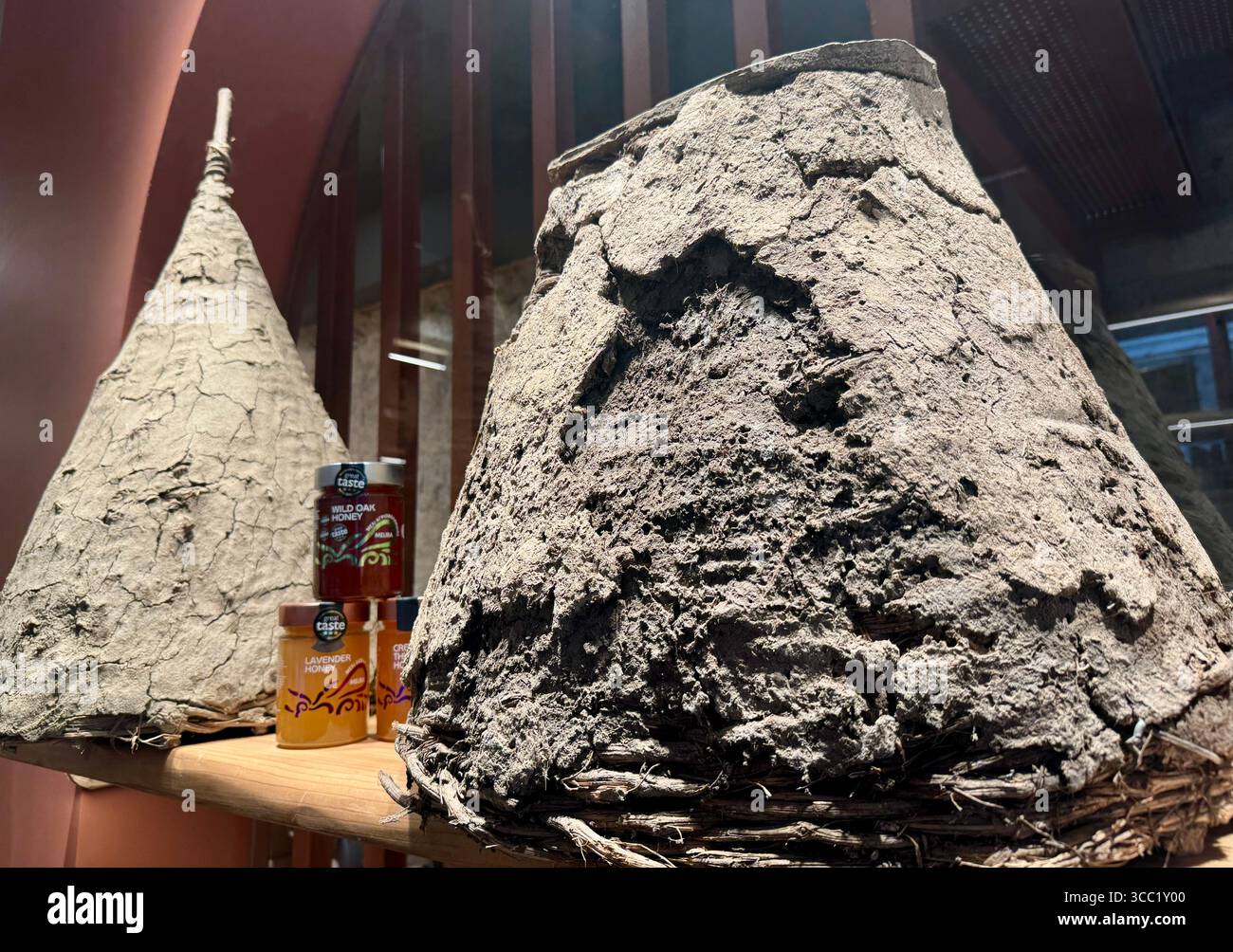 Melira honey jars displayed beside traditional Greek beehives, representing the legacy of a family-run apiculture company in Greece. - Smartphone Captured Stock Image