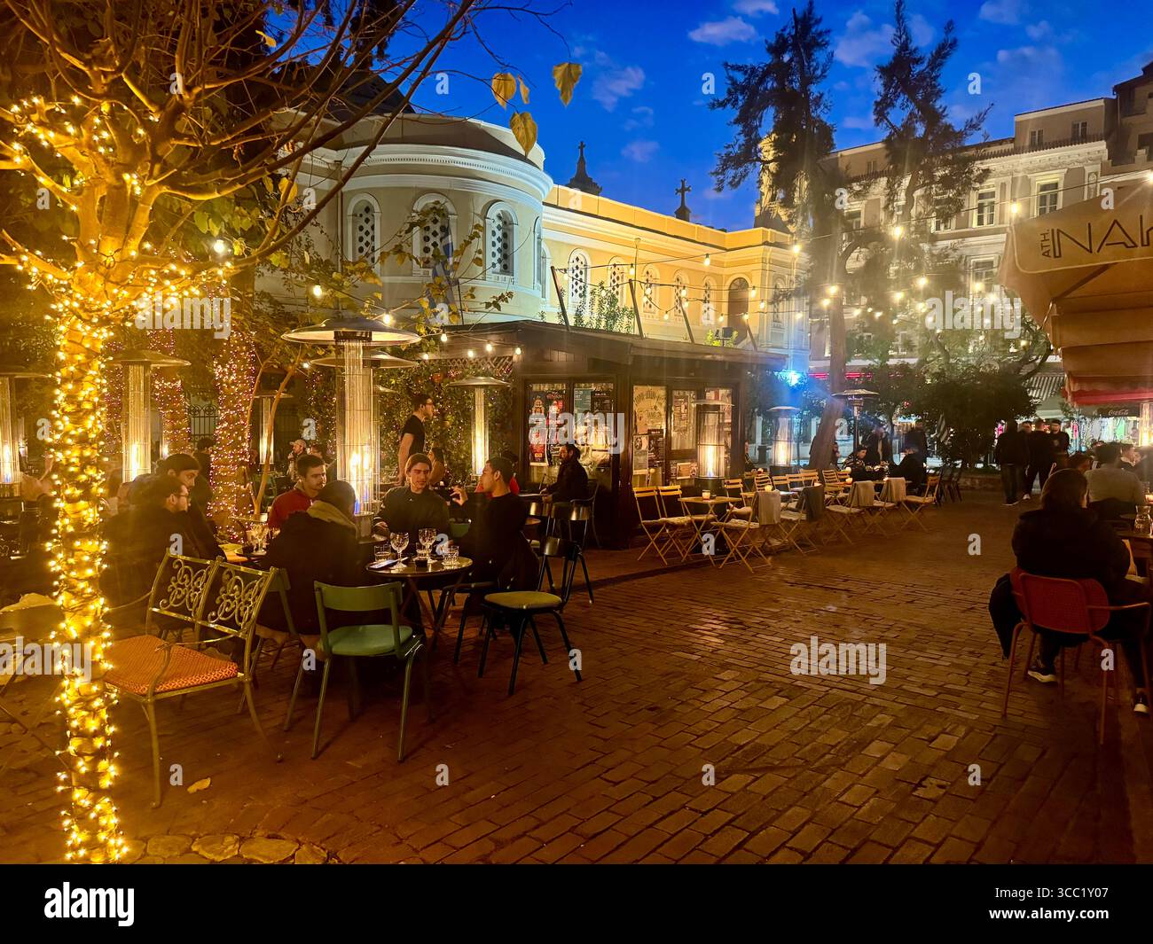 Vibrant city nightlife scene in downtown Athens with people dining outdoors under decorative lights. - Smartphone Captured Stock Image