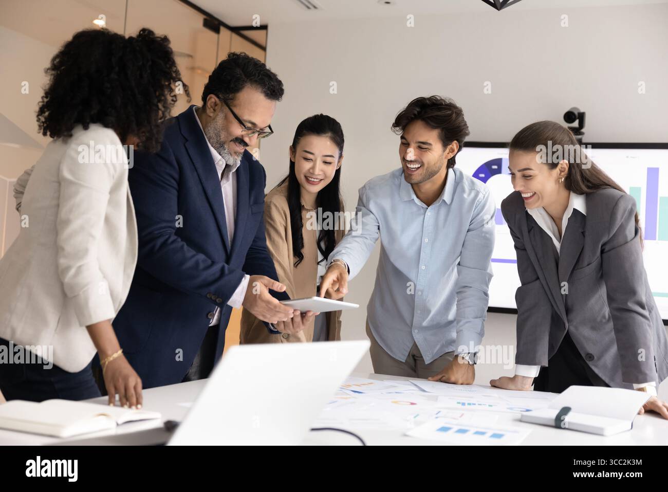 Joyful international analysts group work on project using digital tools Stock Photo