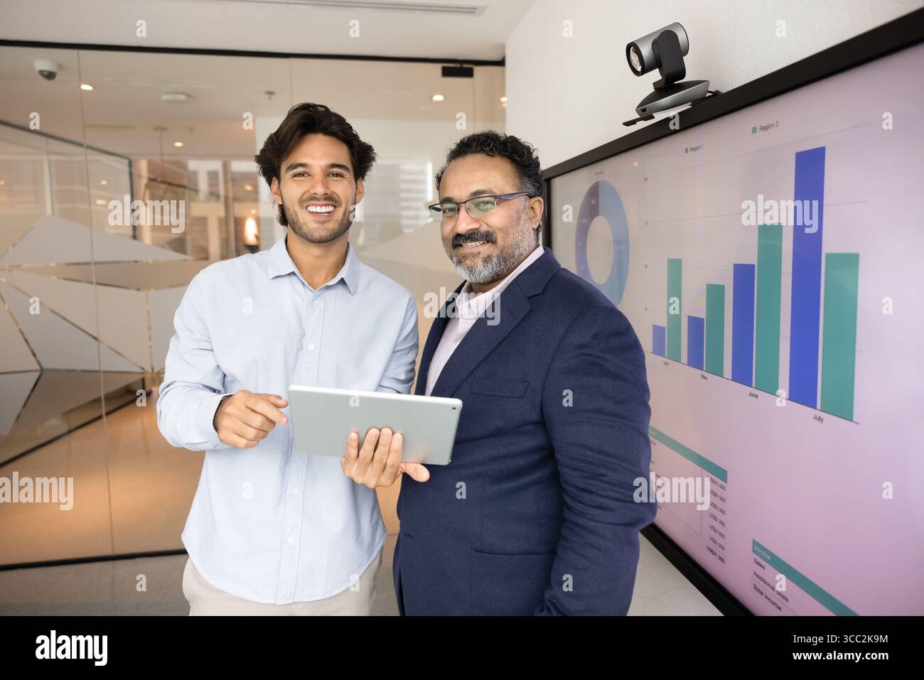 Two businessmen look at camera with happy smiles holding tablet Stock Photo