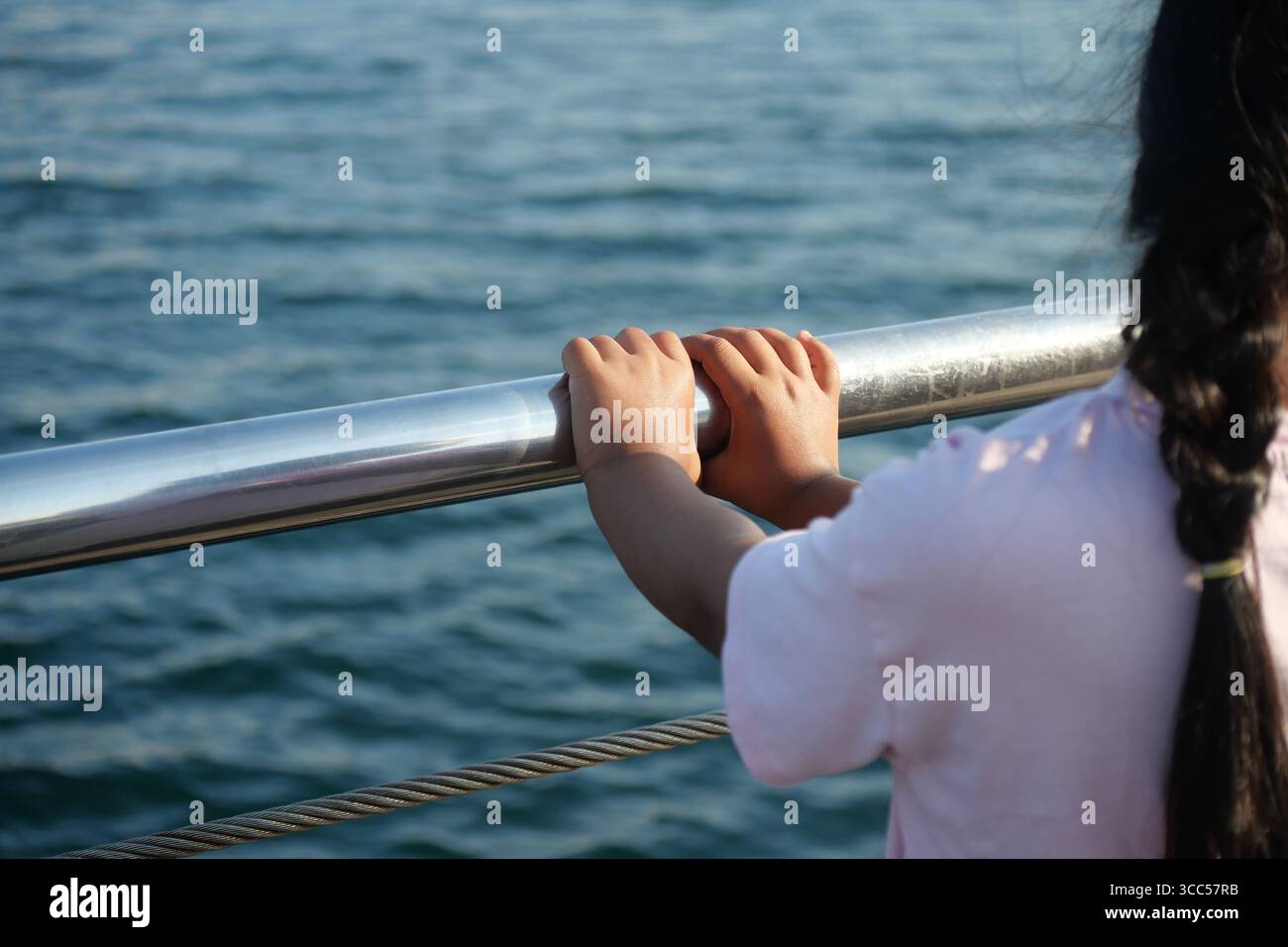 Child enjoys the view while holding onto a boat railing Stock Photo