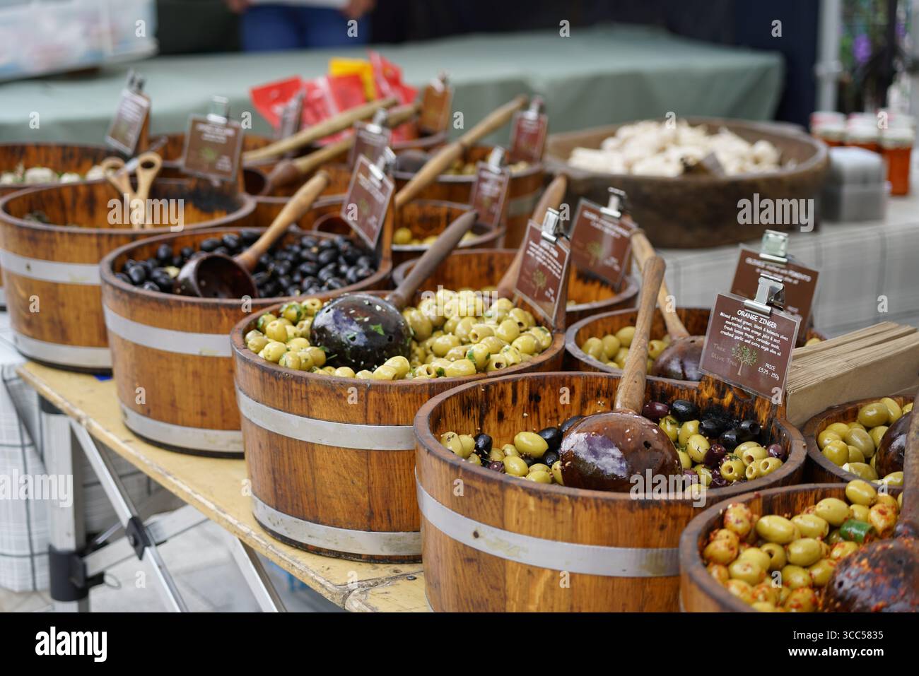 Assorted Olive Varieties Displayed in Rustic Wooden Barrels at Local Market Stall. Salisbury, England Stock Photo