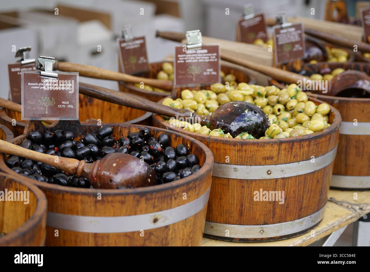 Assorted Olive Varieties Displayed in Rustic Wooden Barrels at Local Market Stall. Salisbury, England Stock Photo