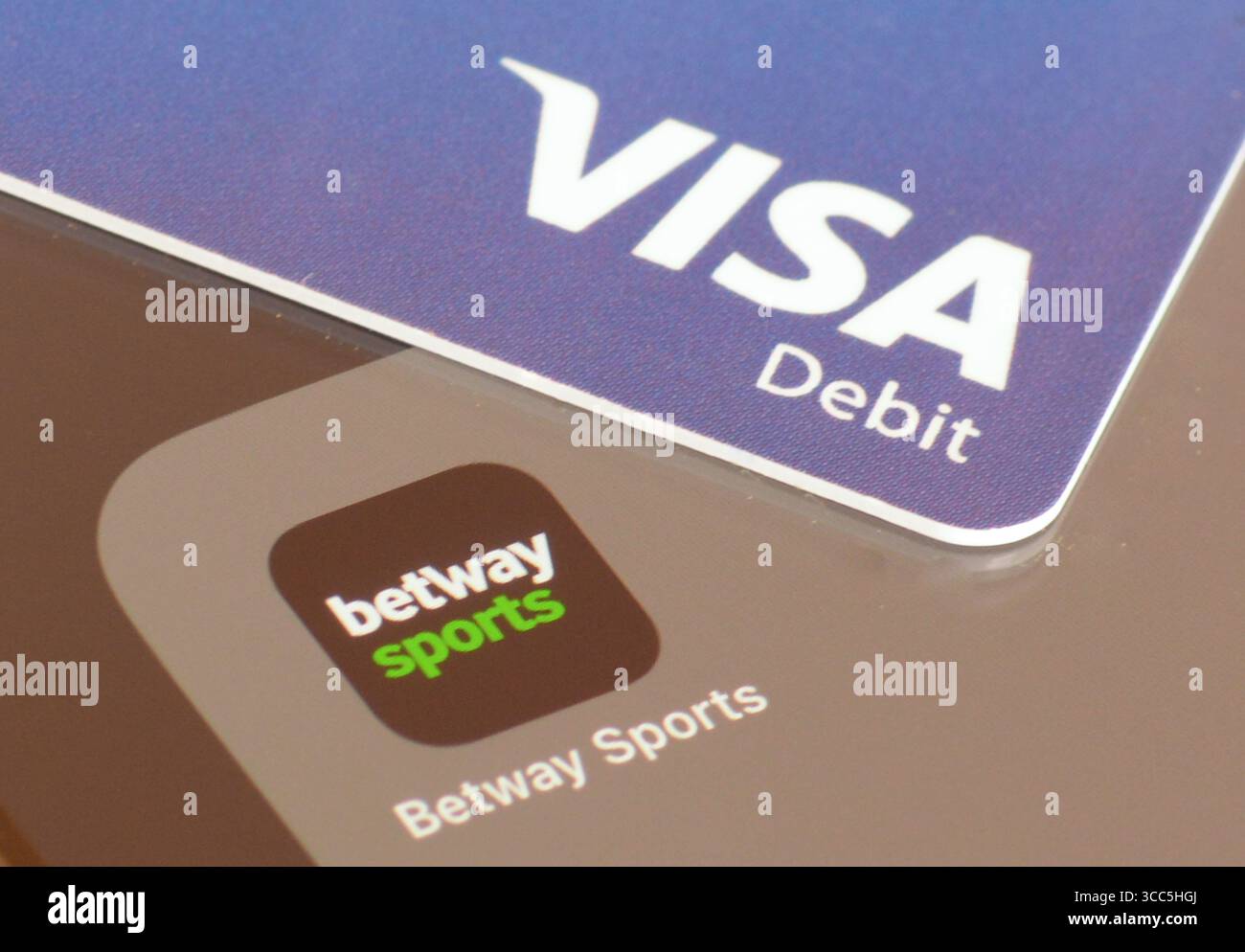 Betway Sports gambling app on smartphone screen with VISA debit card to deposit money Stock Photo