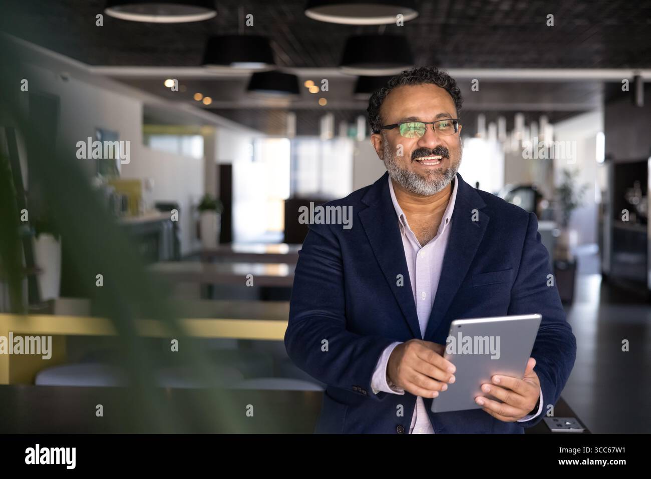 Cheerful elder Indian businessman using tablet computer Stock Photo
