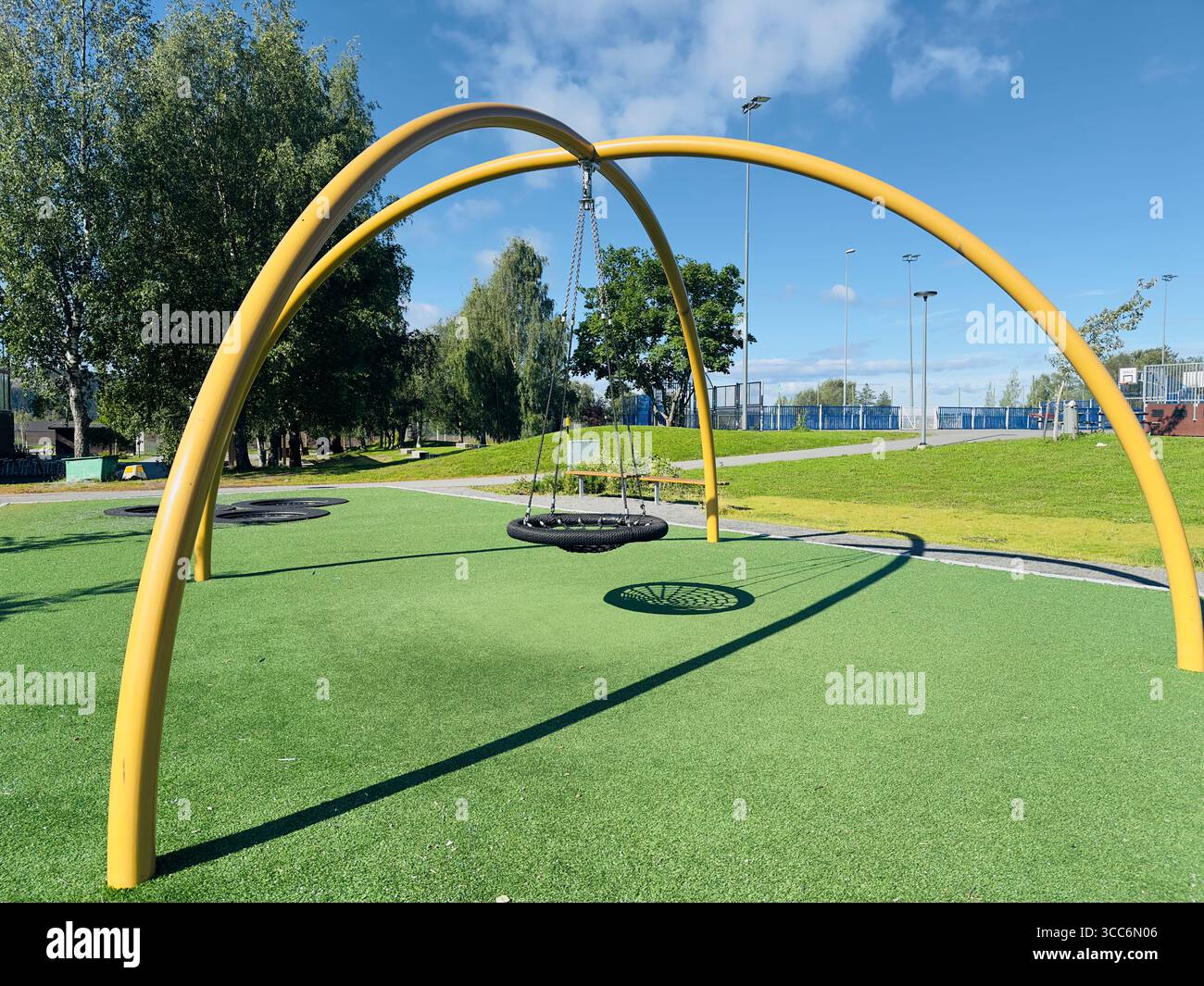 A unique yellow arch swing set at a modern playground on a sunny day. - Smartphone Captured Stock Image A unique yellow arch swing set at a modern playground on a sunny day. - Smartphone Captured Stock Image