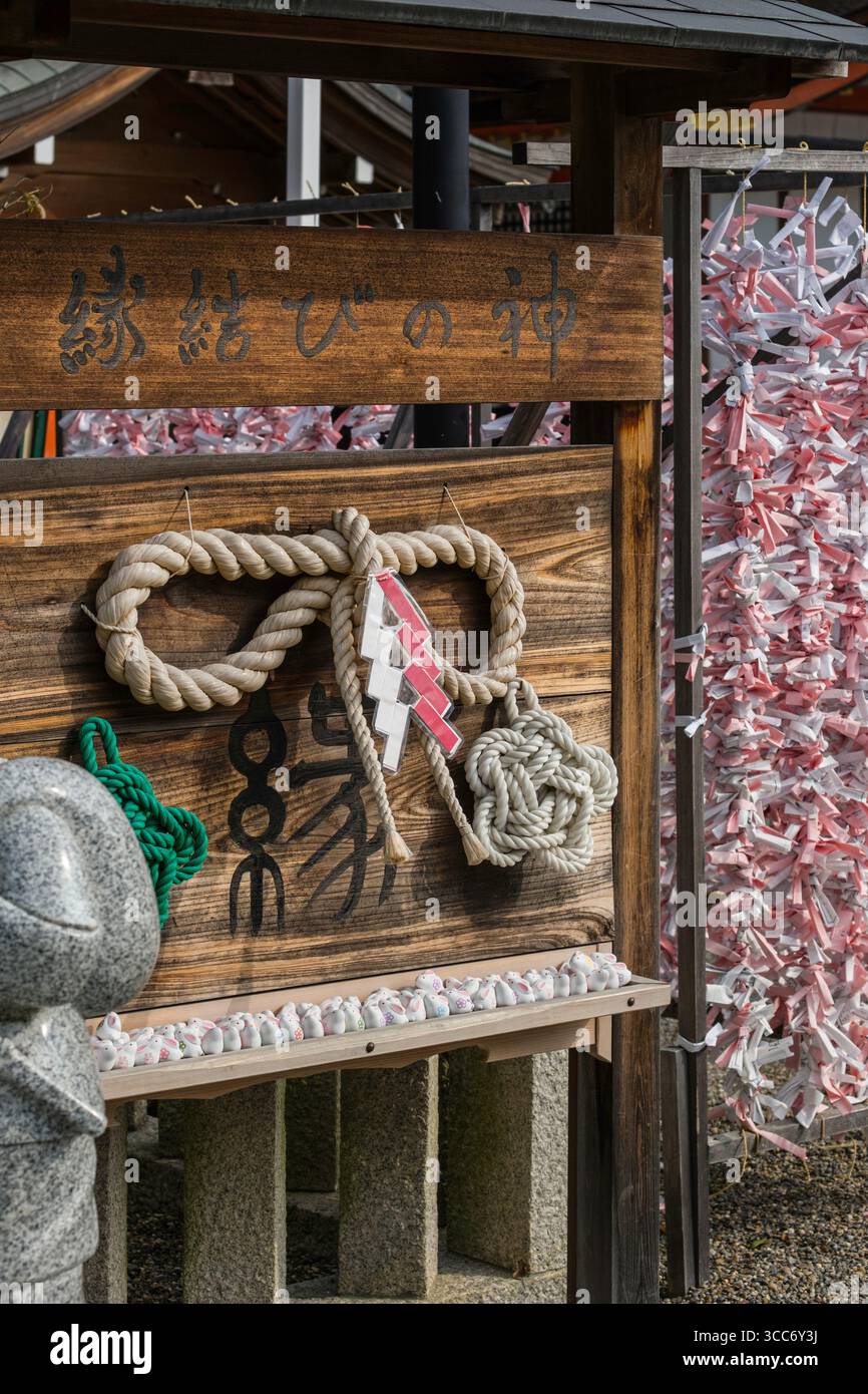 A serene Japanese shrine featuring a decorative rope and wooden sign ...