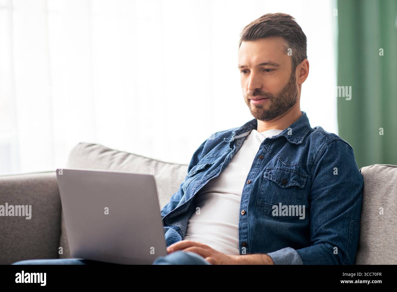 Concentrated man using computer, having part time job at home Stock Photo