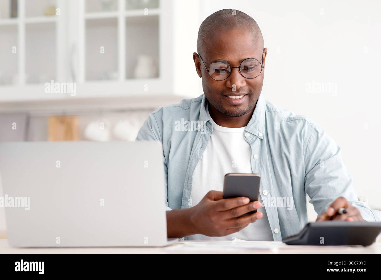 Savings and finances concept. Mature black man using calculator, phone and laptop computer Stock Photo