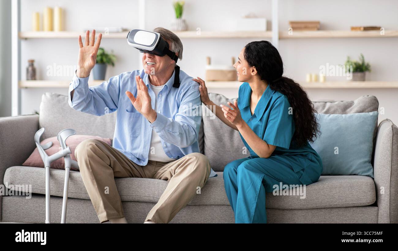Disabled senior man using VR headset with young nurse, exploring augmented reality at home Stock Photo