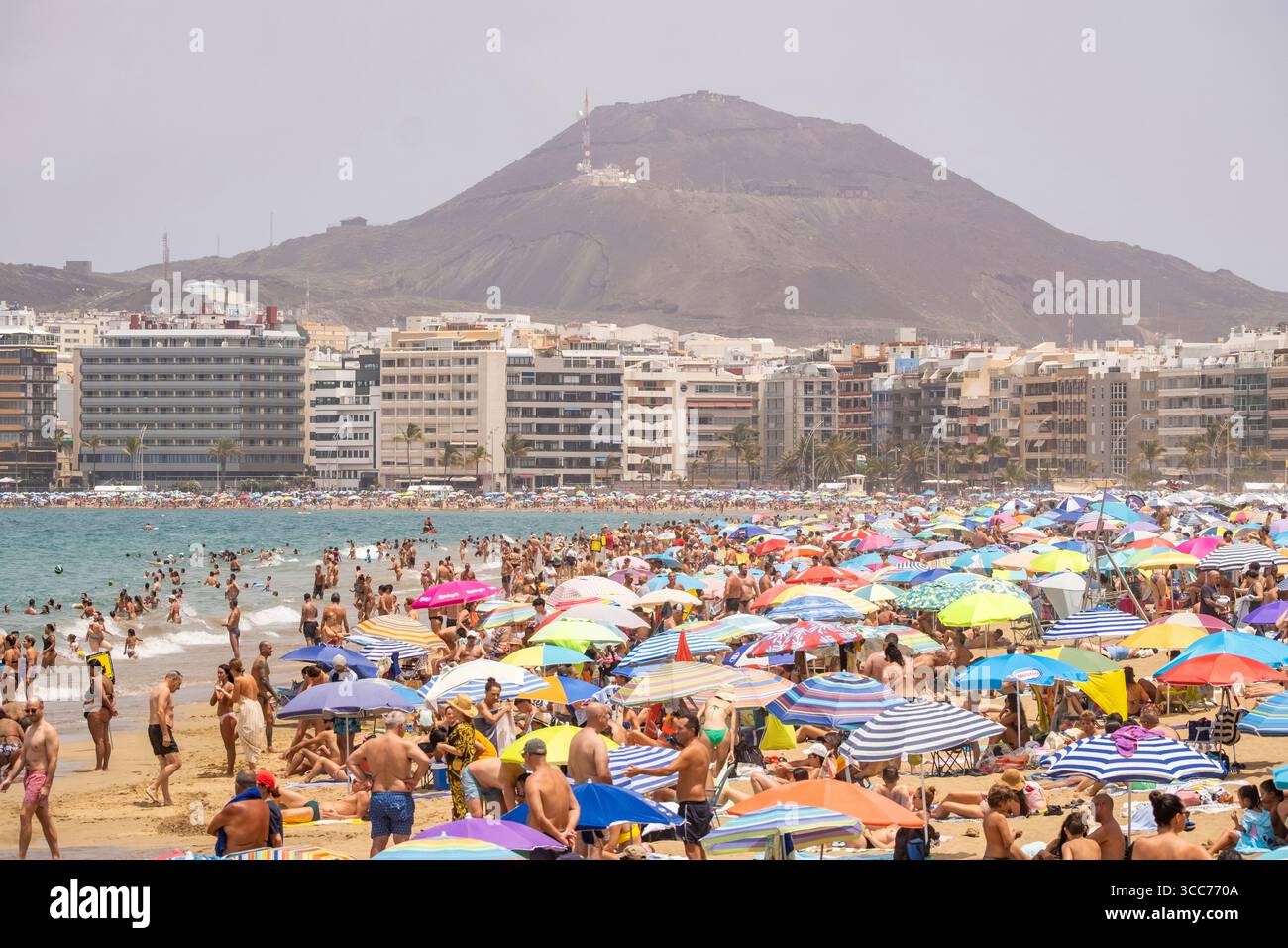Las Palmas, Gran Canaria, Canary Islands, Spain. 10th August, 2025. Tourists, many British, join locals trying to keep cool on a packed city beach in Las Palmas as hot Saharan winds blow dust in from nearby Africa, reducing visibility and air quality. Red heatwave alerts have been activated across all the Canary Islands for the weekend and early next week. The temperature reached 43.5 Celcius in the south of Gran Canaria on Saturday, with hotter weather forecast for Sunday. Credit: Alan Dawson/Alamy Live News Stock Photo