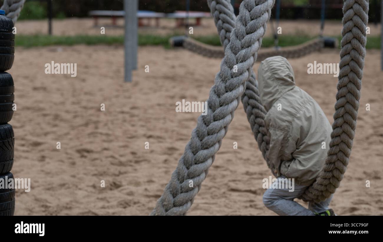 Child playing on rope swing at sandy playground Stock Photo - Alamy