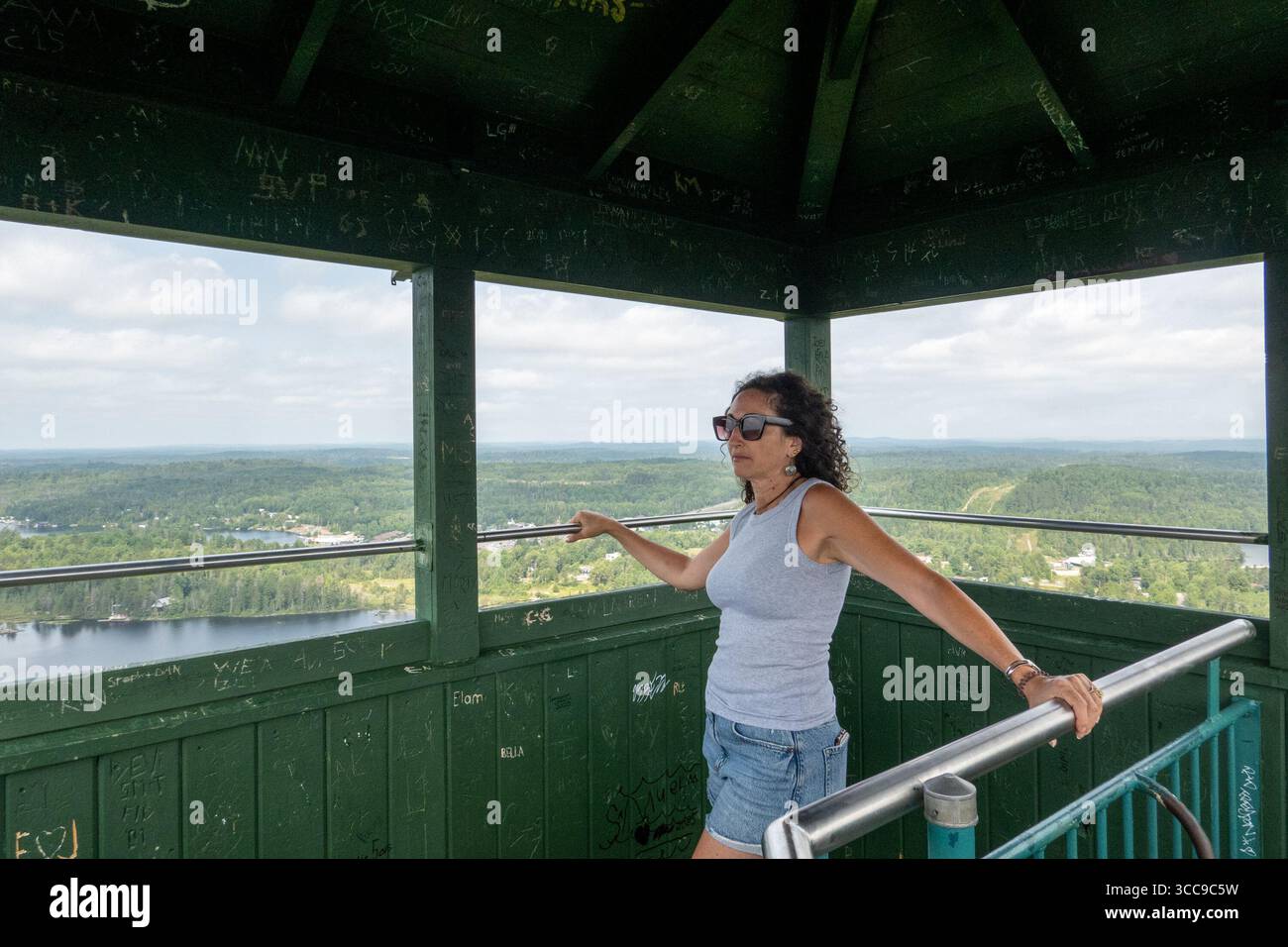 Temagami, Canada. 09th Aug, 2025. Tourist enjoys the view from top of Temagami Fire Tower. The Temagami Fire Tower, perched atop Caribou Mountain in Northeastern Ontario, offers panoramic views of the surrounding old-growth forests and Lake Temagami. Standing 100 feet tall, this steel structure was originally constructed in 1910 and has been restored to serve as a public lookout and historical site. Credit: SOPA Images Limited/Alamy Live News Stock Photo