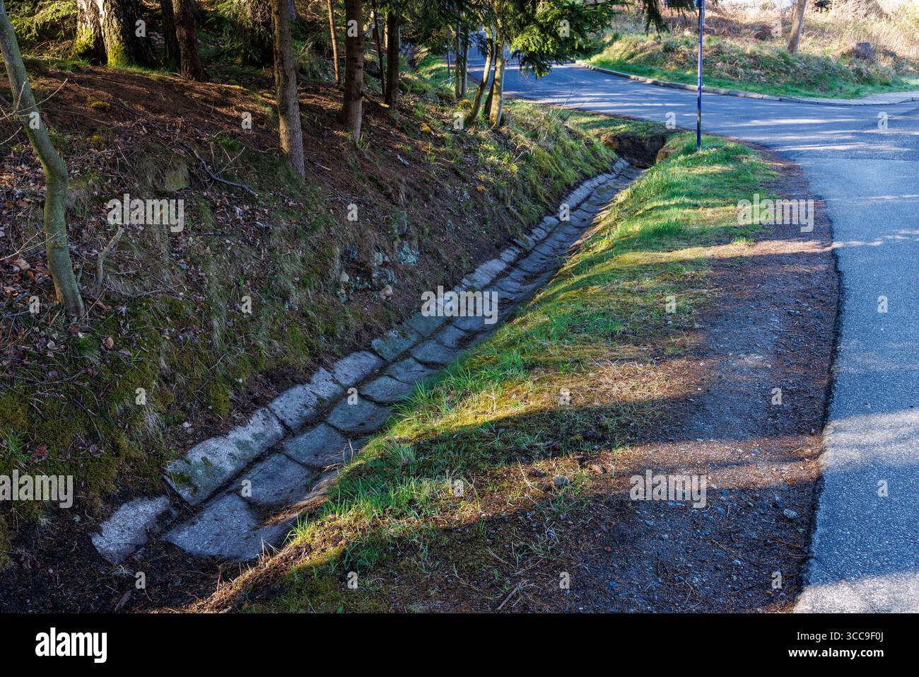 Rainwater drainage gutter made of concrete blocks along an asphalt road ...