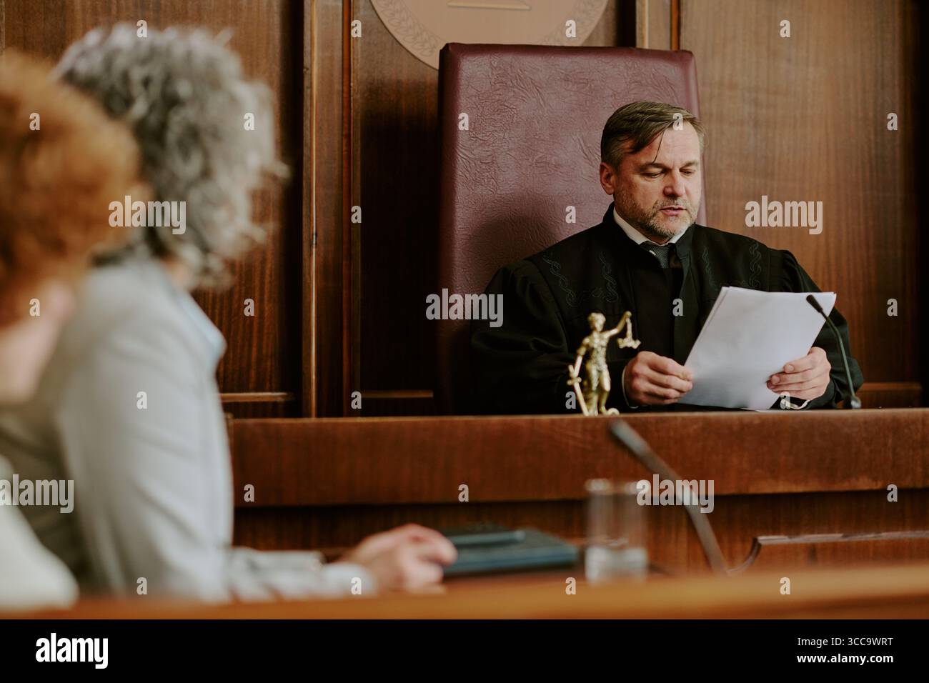 Middle Aged Caucasian Male Judge Reading Legal Documents during Court Hearing Stock Photo