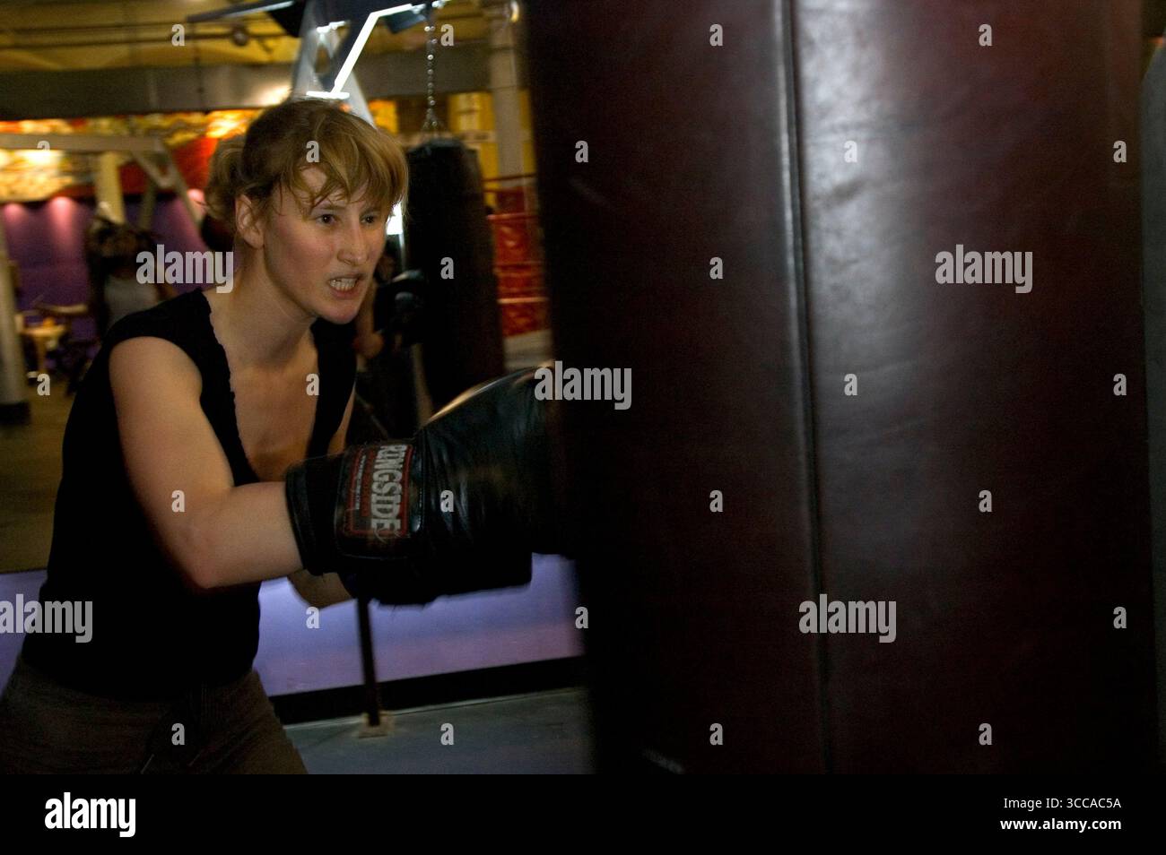 A young woman practices boxing with a punching bag Stock Photo