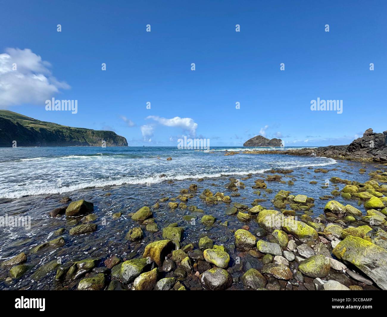Low tide at Mosteiros Beach, Azores, Portugal, with green volcanic rocks and the famous Mosteiros islets in the distance. - Smartphone Captured Stock Image