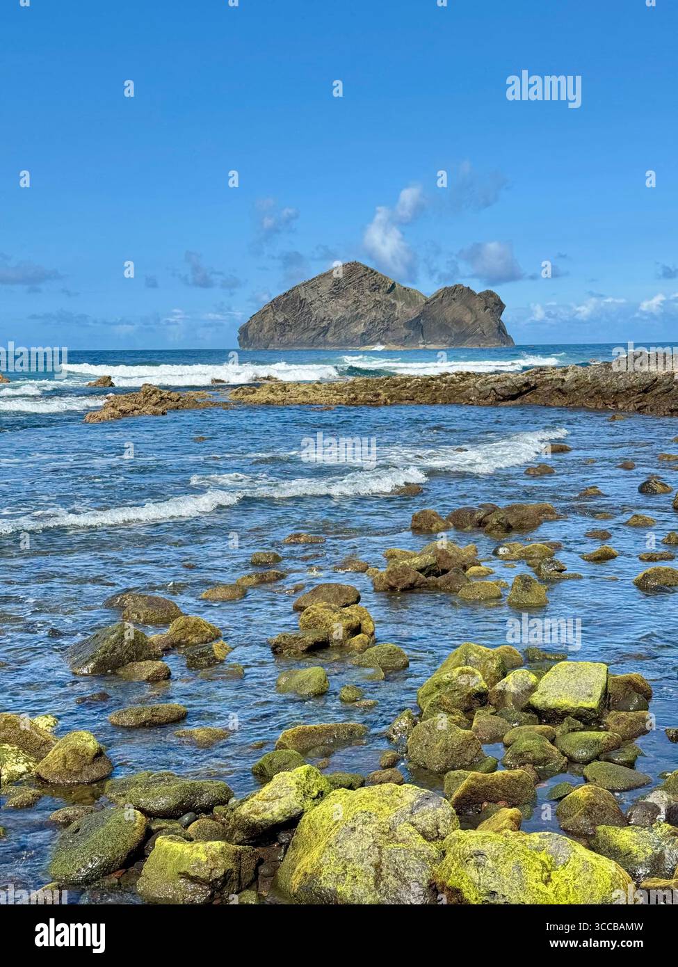 Low tide at Mosteiros Beach, Azores, Portugal, with green volcanic rocks and the famous Mosteiros islets in the distance. - Smartphone Captured Stock Image