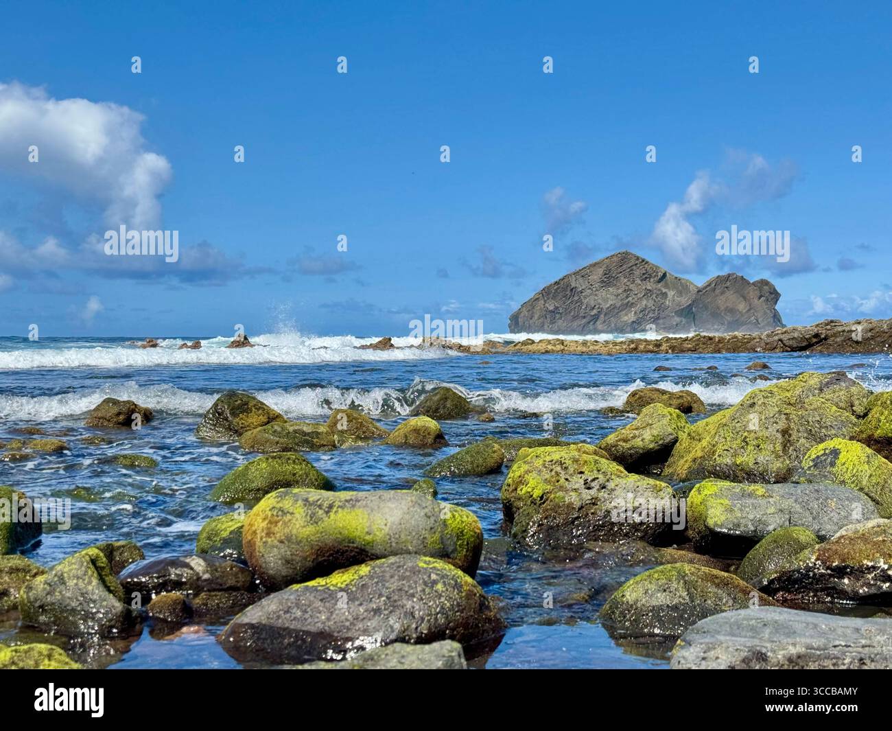 Low tide at Mosteiros Beach, Azores, Portugal, with green volcanic rocks and the famous Mosteiros islets in the distance. - Smartphone Captured Stock Image