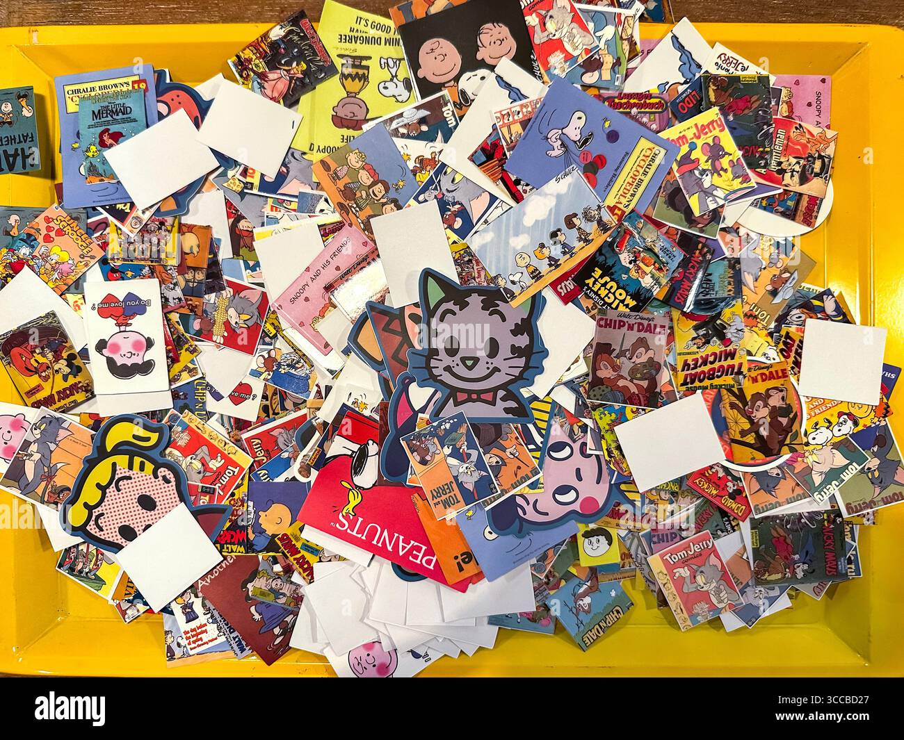 A colourful assortment of vintage cartoon and comic stickers featuring various popular characters on a yellow tray junk shop kuala lumpur malaysia - Smartphone Captured Stock Image